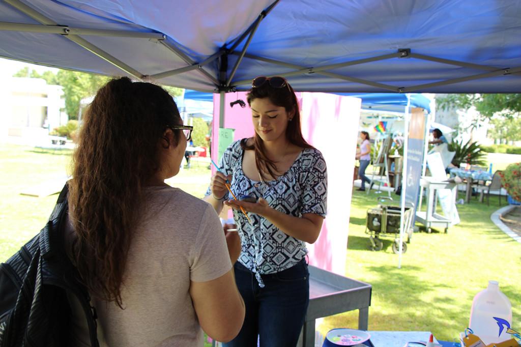 Trevante Hammonds/The Runner Freshman Alex Accord and freshman geology major Wendy Mendez, paint on rocks at the DIY management booth on Wednesday, May 11 outside the Student Union patio.