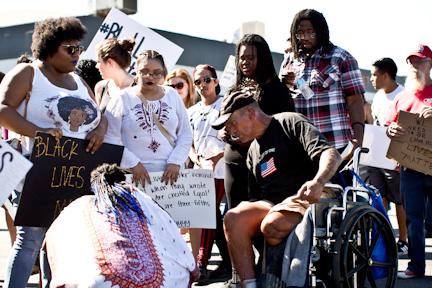 During the protest, protestors stopped to help the man in the wheel chair cross the street along with providing him with a bottle of water. AJ Alvarado/The Runner