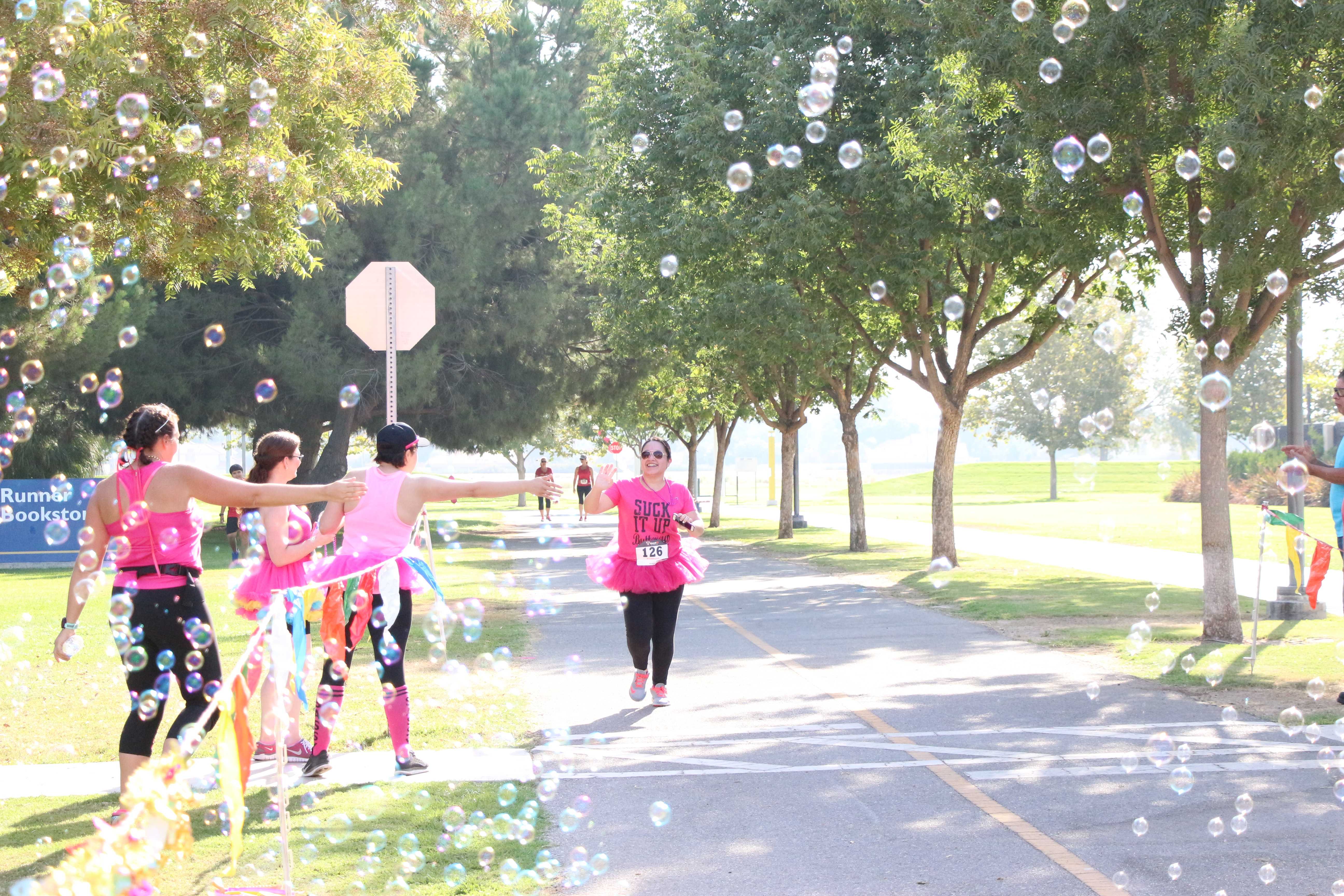 Participants in tutus high-fiving their teammate as she is reaching the finish line of the 5K Fun Run course benefitting the organization Dress for Success on Saturday at CSUB. Photo by Alejandra Flores/ The Runner
