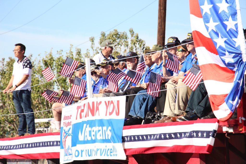 Multiple veterans wave flags as they ride in the Veterans Day Parade Friday, Nov. 11 in downtown Bakersfield. Photo by Alejandra Flores/The Runner