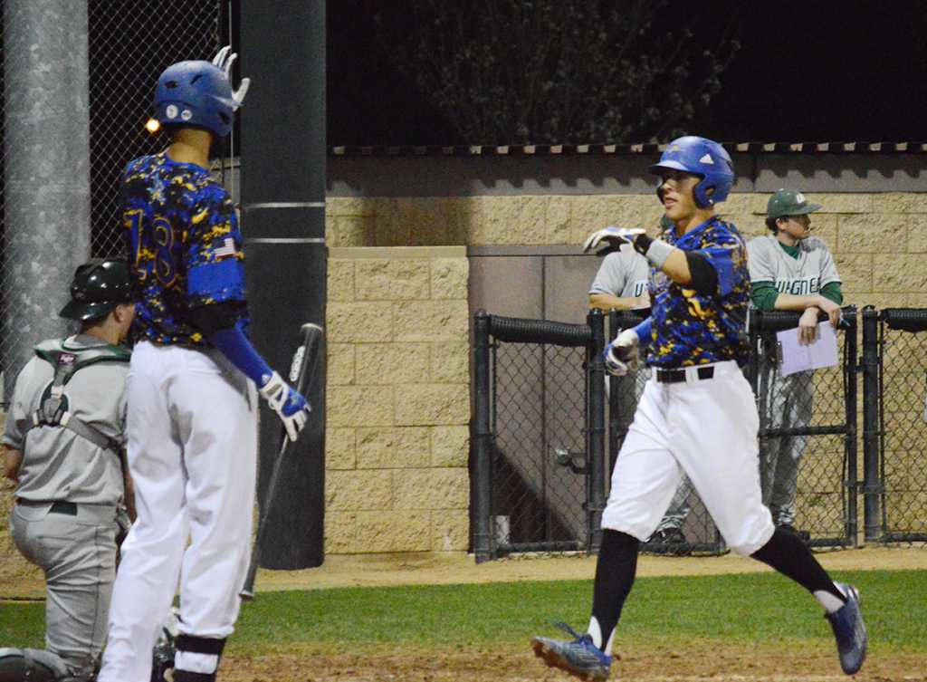 Senior Solomon Williams gives sophomore teammate Joey Sanchez a high five after driving in a run against Wagner University on March 8.
Photo by Eric Garza/The Runner