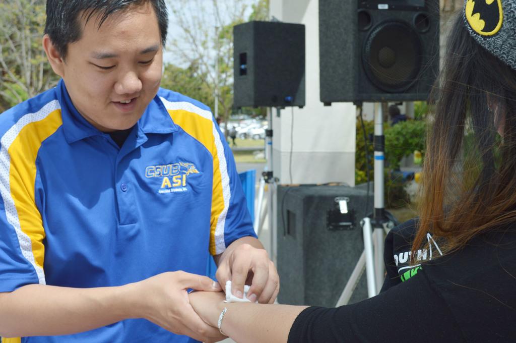 Mike Kwon, ASI and CSUB Fashion Club member, gives Cristal Mondragon, junior, a flash tattoo at the CSUB Fashion Club fundraiser on April 7.