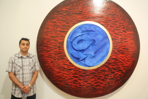 Jose Bravo posing next to his art work "Lil Bit of Rock n' Roll, Lil' bit of Hip Hop, and Lil' bit of Japan during the opening of Nexus senior art exhibition on Thursday, May 14 at Todd Madigan Gallery 