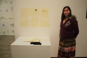 Caroline Gaete posing next to " book of studies and oddities" the opening of Nexus senior art exhibition on Thursday, May 14 at Todd Madigan Gallery 