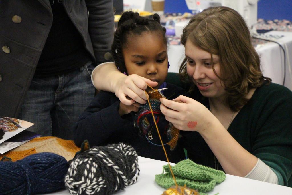 : Elizabeth Lewis teaching 3-year-old Lula Wyatt how to knit at the Maker Faire on Saturday. 
By Alejandra Flores/ The Runner