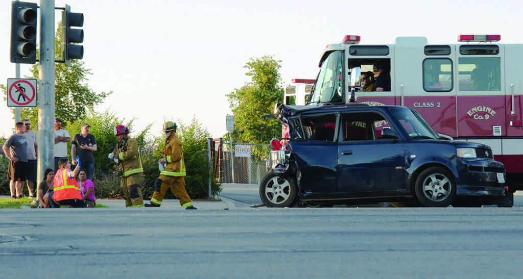 The two passengers from the black Scion get checked on after the card accident on Tuesday. Photo by Ben Patton/The Runner