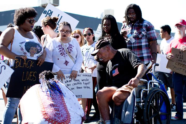Participants of the protest stop to help a man in a wheel chair cross the street and give him some water on Saturday, July 9.
Photo by AJ Alvarado/The Runner
