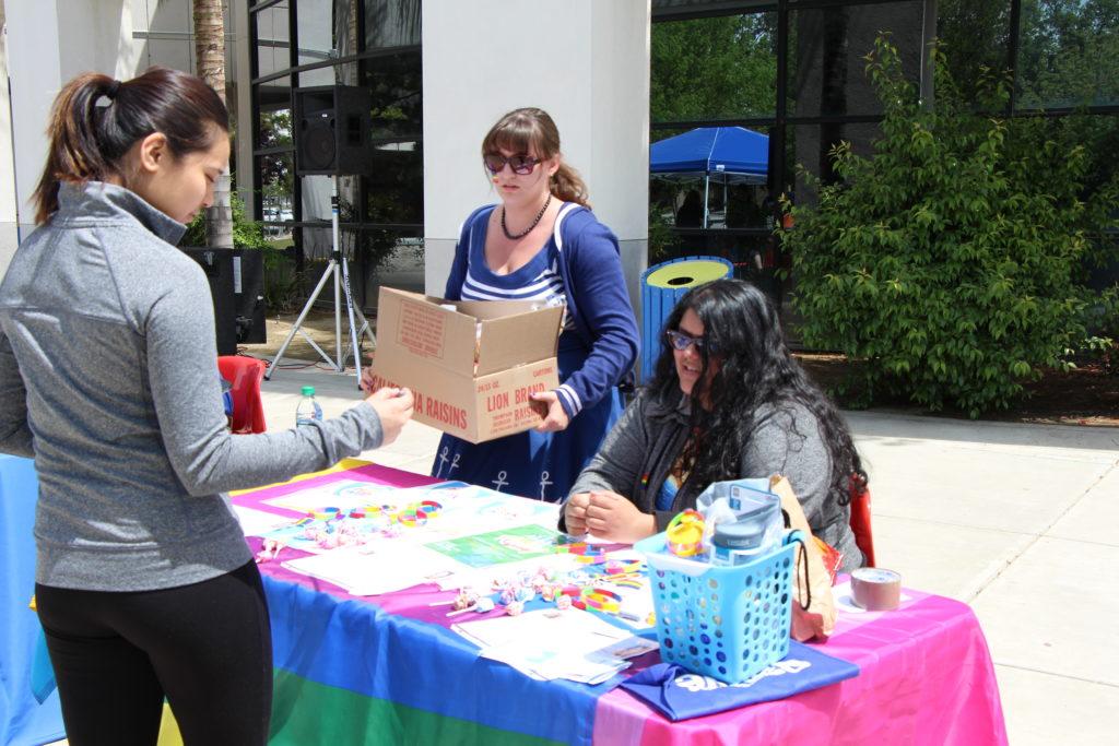 Criminal justice major Alyssa Olivara, 24, hands out candy and wristbands at her booth at the Consent Carnival during Pride Week at the Student Union Patio on Monday, April 17. Photo by Kabria Dodley/ The Runner 