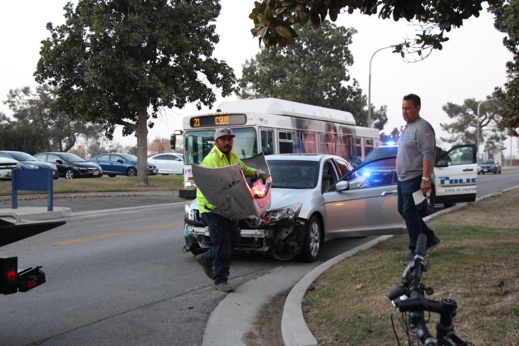 Photo by Brenda Gonzalez/The Runner
A tow truck driver picks up the bumper of a disabled Honda Accord after a collision with a Chevrolet Colorado on Thursday Dec. 14. 