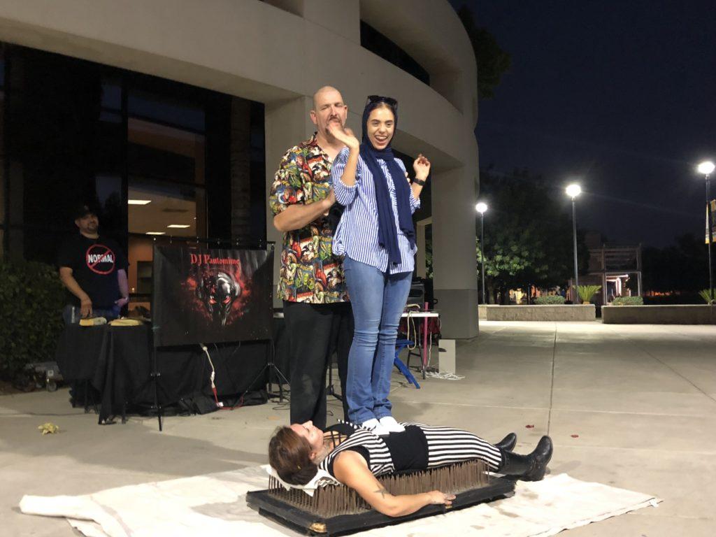 Shaima Aldhulay, freshman at CSUB, stands on Kali Spinner as she lays on a bed of nails. Kayla Olivieri / The Runner