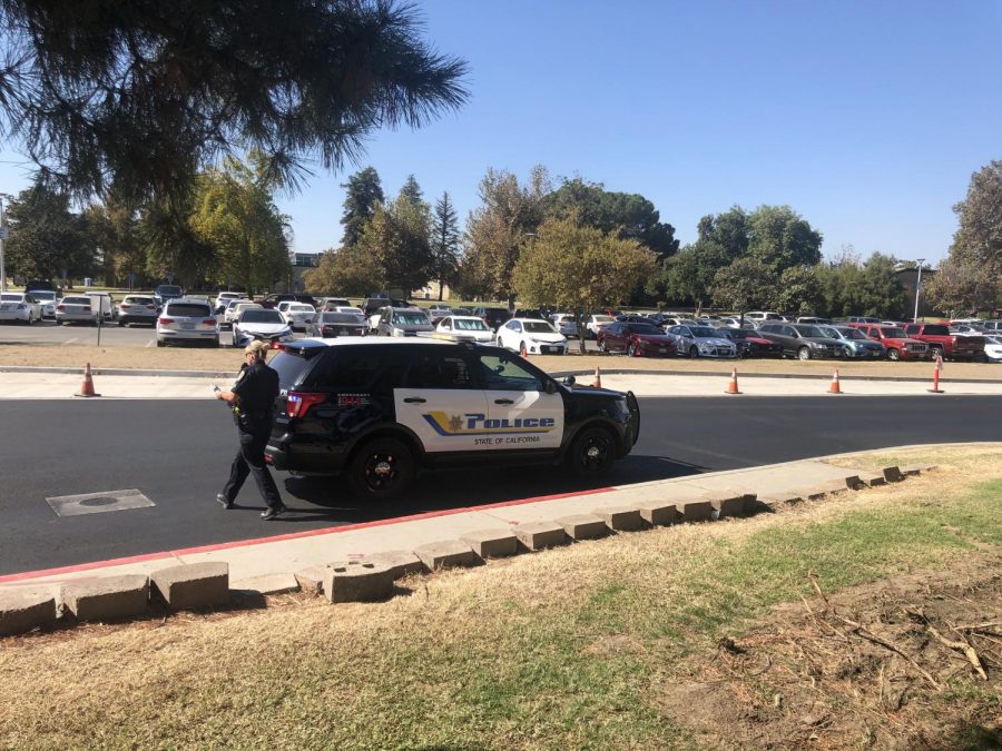 Officer Martinez walking to the driver's side of car after placing suspect inside. Photo by Damian Lopez