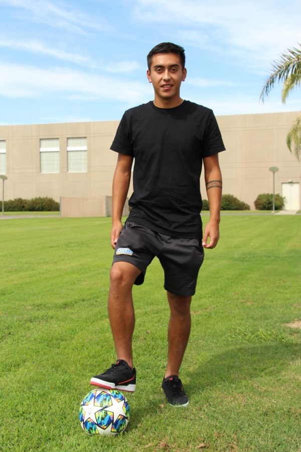 Carlos Armendariz, sophomore midfielder, poses with soccer ball near the main soccer field.