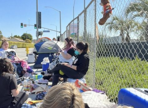 Fans sitting in chairs waiting in the streets for the concert to start. 