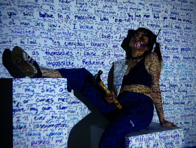 Lucia posing in the projection of her poem for her multi-media piece “Find Comfort in Your Skin” / Provided by Lucia Guzman.
