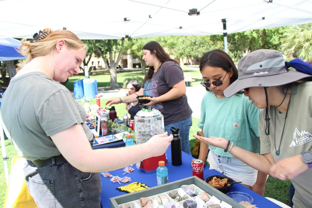 CSUB geology club shows students different rocks that are collected by the department of geology.  Allyssa Tafoya, Geology major, and Monica Hinson, Geology lecture, help Rose Odell figure out what rock she got from their rock vending matchine game. 
