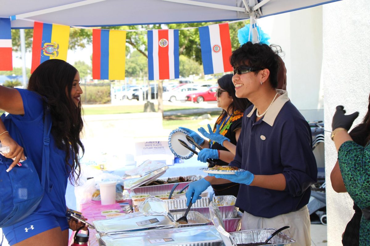  Kyle Capulong, Campus Programing student worker, serves food to Jahnyl Howden, Business Marketing major, at the Latinx Heritage Month Kickoff event. 